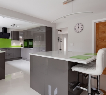 Contemporary fitted kitchen in striking lime green, grey and white colour scheme with built in appliances, white granite counter tops dual ovens island breakfast bar and hob
